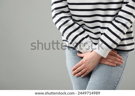 Woman suffering from cystitis on grey background, closeup. Space for text Royalty-Free Stock Photo #2449714989