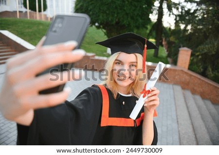 Female graduating student in bachelor robe taking selfie on her graduation day.
