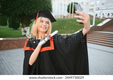 Female graduating student in bachelor robe taking selfie on her graduation day.