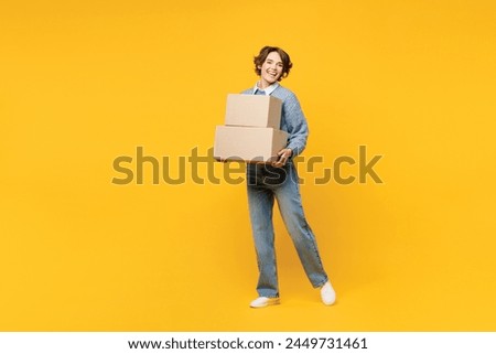 Full body young happy cheerful woman she wears grey knitted sweater shirt casual clothes hold cardboard boxes look camera isolated on plain yellow color background studio portrait. Lifestyle concept Royalty-Free Stock Photo #2449731461