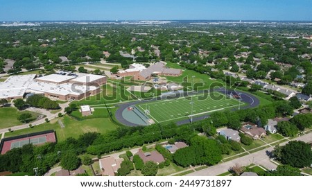 Middle school football field stadium and tennis courts situated in an upscale residential neighborhood suburbs Dallas, Texas, single family homes with swimming pool, grassy front yard, aerial. USA Royalty-Free Stock Photo #2449731897