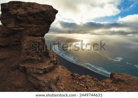 The photo shows a beautiful sunset on Lanzarote, taken from a high cliff overlooking the sea. The vibrant colors of the sky reflect off the calm waters below, creating a peaceful atmosphere.