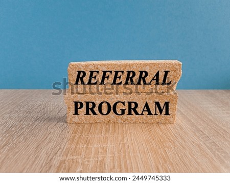 Brick blocks with words REFERRAL PROGRAM. Beautiful blue background, wooden table. copy space. Business concept.