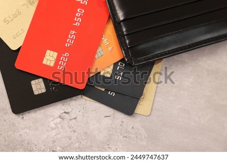 Many different credit cards and leather wallet on grey table, top view