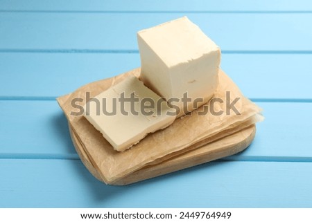 Block of tasty butter on light blue wooden table
