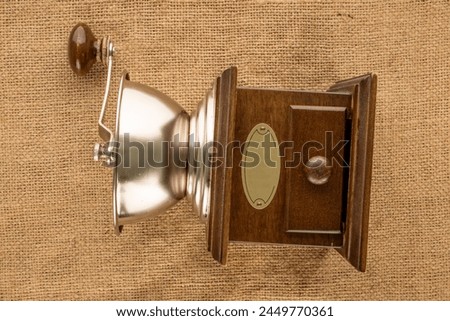 One manual, wooden coffee grinder on a jute cloth, macro, top view. Royalty-Free Stock Photo #2449770361