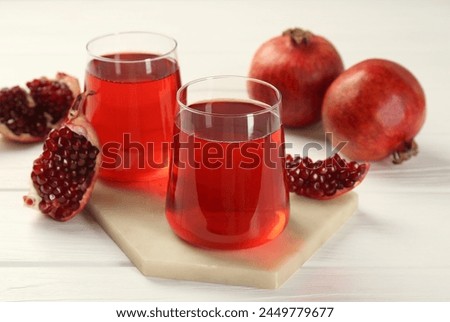Tasty pomegranate juice in glasses and fresh fruits on white wooden table