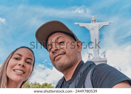 A man and a woman are posing for a picture in front of a statue of Jesus Christ, archs of Acuchimay, Ayacucho. Peru
