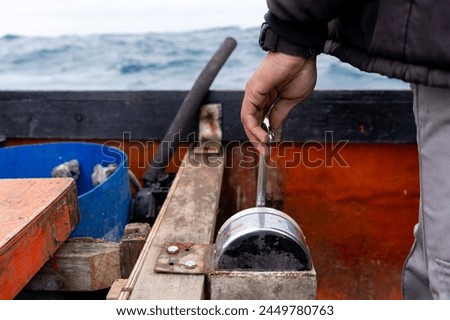 Close-up photo of the hand of a lobster fisherman driving a boat along ocean