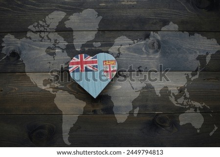 wooden heart with national flag of Fiji near world map on the wooden background. concept
