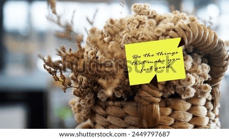 Inspirational motivational quote - Do the things that make you feel good. Text message on a yellow notepaper on white cream edelweiss dried flower bouquet on natural wooden basket. Happiness concept.