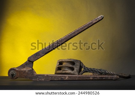 Ancient wood equipment:  compass and marine pulley with rope. Studio light, yellow background.