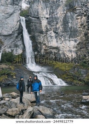 Three people standing in front of a waterfall