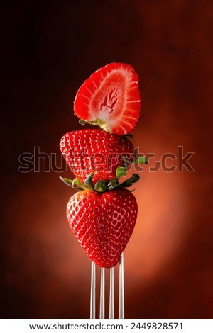 Fork with strawberries close-up on black background with red glow. still life