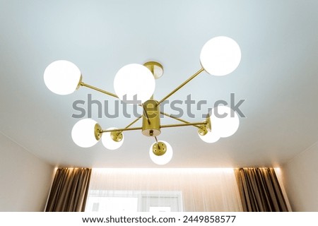 An elegant chandelier made of wood and with tints and shades is hanging from the ceiling in a bedroom, adding a touch of sophistication to the interior design