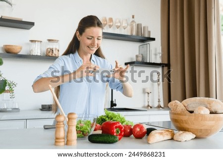 Happy Caucasian woman food blogger taking photo of cooking process at home kitchen. Chef young housewife blogging vlogging online for social media, preparing vegan meal food