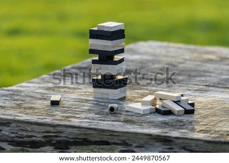 Peaceful rest in nature in sunny weather. The game "Jenga", "Wooden tower" against the background of nature. Concentration, calmness, choice, decision-making. High quality photo Royalty-Free Stock Photo #2449870567