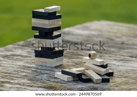 Peaceful rest in nature in sunny weather. The game "Jenga", "Wooden tower" against the background of nature. Concentration, calmness, choice, decision-making. High quality photo Royalty-Free Stock Photo #2449870569