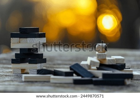 Peaceful rest in nature in sunny weather. The game "Jenga", "Wooden tower" against the background of nature. Concentration, calmness, choice, decision-making. High quality photo Royalty-Free Stock Photo #2449870571