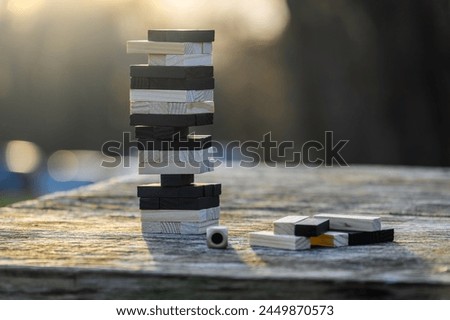 Peaceful rest in nature in sunny weather. The game "Jenga", "Wooden tower" against the background of nature. Concentration, calmness, choice, decision-making. High quality photo Royalty-Free Stock Photo #2449870573