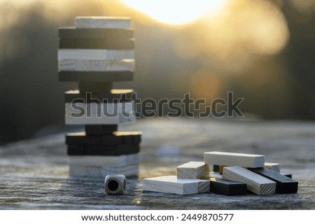 Peaceful rest in nature in sunny weather. The game "Jenga", "Wooden tower" against the background of nature. Concentration, calmness, choice, decision-making. High quality photo Royalty-Free Stock Photo #2449870577