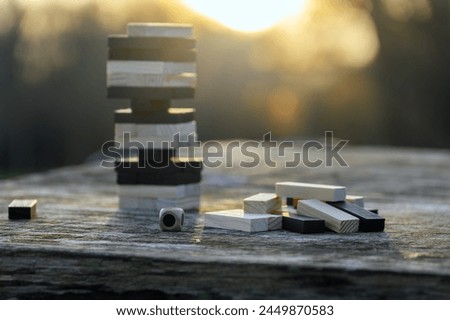 Peaceful rest in nature in sunny weather. The game "Jenga", "Wooden tower" against the background of nature. Concentration, calmness, choice, decision-making. High quality photo Royalty-Free Stock Photo #2449870583