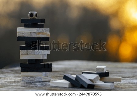 Peaceful rest in nature in sunny weather. The game "Jenga", "Wooden tower" against the background of nature. Concentration, calmness, choice, decision-making. High quality photo Royalty-Free Stock Photo #2449870595