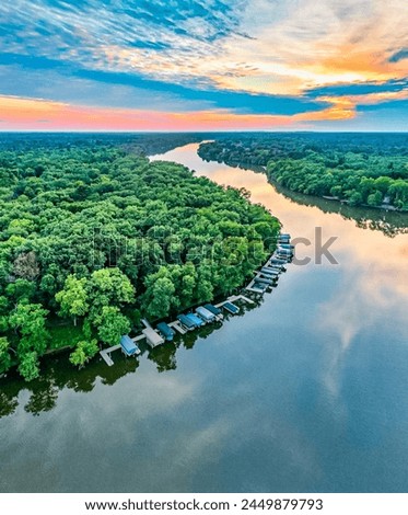 Breathtaking Aerial Sunset View Over Serene Lake, Lush Green Forest, Reflective Water Surface, Docked Boats, Vibrant Sky - Perfect Natural Landscape for Relaxation and High-Quality Wallpaper Image.”