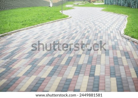City street paved with three-color paving slabs. Sidewalk with gray, yellow and red cement rectangular tiles. Multi-colored paints of a modern city. Selective focus.
