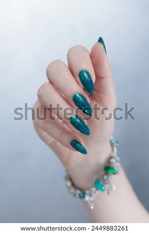 Woman's hand with long nails and green nail polish