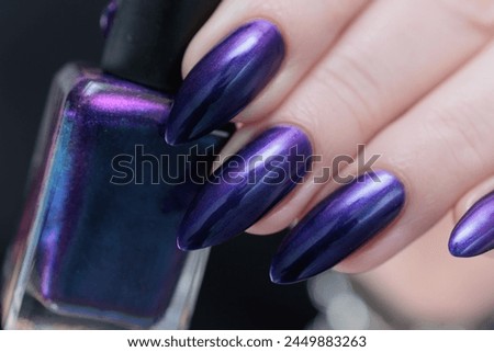 Female hands with long nails and dark black purple manicure 