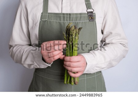 Green asparagus in the hands of a men. Bunch of ripe fresh asparagus. Healthy organic food. Cooking in home. Natural vitamins, raw ingredient for eating. Handpicked bio asparagus Royalty-Free Stock Photo #2449883965