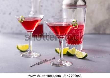 Martini cocktail with cranberry juice garnished with a lime twist Royalty-Free Stock Photo #2449909063