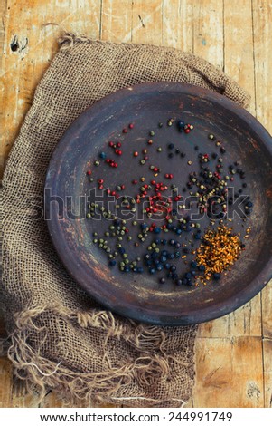 Overhead view of varieties of pepper corns in an old plate including, black, white, pink and mixed whole dried peppercorns isolated on Vintage table Background.