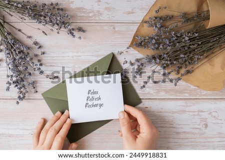 RELAX REFRESH RECHARGE text on supportive message paper note reminder from green envelope. Flat lay composition dry lavender flowers. Concept of inner happiness, slowing-down digital detox personal Royalty-Free Stock Photo #2449918831