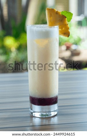 a glass of pineapple juice served with ice is placed on the table. consist of pineapple juice and sugar syrup