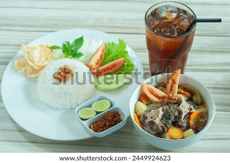 Beef rib soup rice is served in a plate with white rice and chili sauce