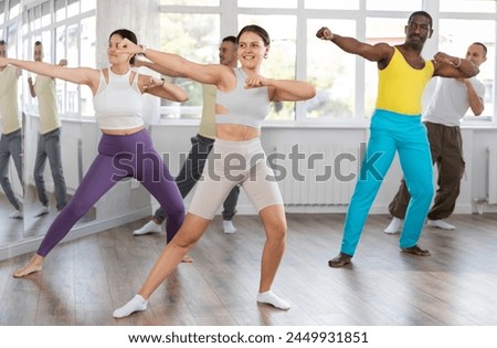 European girl practices kicking and punching in process of self-defense. Multinational group activities, wrestling, maintaining physical fitness.