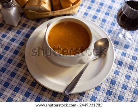 Appetizing tomato soup cooked in meat broth served in white tureen .. Royalty-Free Stock Photo #2449931985