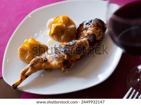 Picture of tasty baked quarter of rabbit, served with pototoes at plate