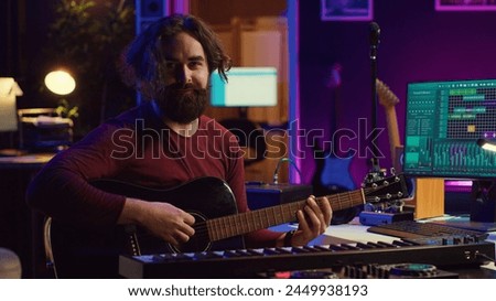 Portrait of artist recording tunes on daw software with his guitar, enjoying time in his home studio office. Audio engineer and musician creating new tracks, stereo electronic instruments. Camera A.