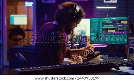 Music engineer using usb stick to edit and add sound effects on audio recording, adjusted volume levels. Artist doing mixing and mastering technique on soundboard, plays piano. Camera A. Royalty-Free Stock Photo #2449938199