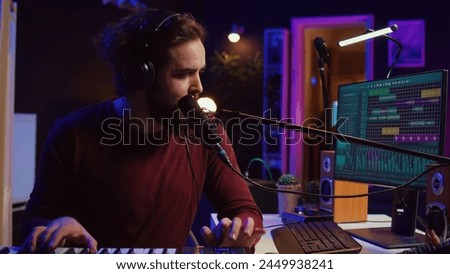 Songwriter recording a new song with microphone and midi controller, playing piano keys in home studio. Talented artist producing music with modern electronic keyboard and tools. Camera B.