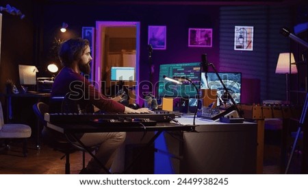 Music producer operating with electronic setup of home studio, recording acoustic guitar sounds. Artist navigating signal processing activity, utilizing digital audio workstation at desk. Camera B.