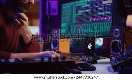 Songwriter creating a special song before recording tunes on musical instruments, writing down the words and melodic elements at his home studio. Artist producing sounds with DAW software. Camera B.