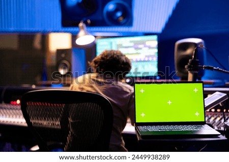 Musician and sound engineer working on a new song with isolated screen, editing and adjusting volume levels on tunes recorded. Team of artists producing music and composing tracks in control room.