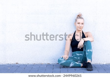 This captivating shot captures the essence of sport and lifestyle as an attractive blonde millennial woman takes a well-deserved break after an invigorating outdoor workout. Her sporty aura is Royalty-Free Stock Photo #2449960261