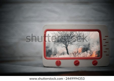 a toy television on the carpet containing a picture of a forest fire


