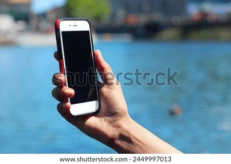 A mock-up of a selfie phone held in hand, background pack and water
