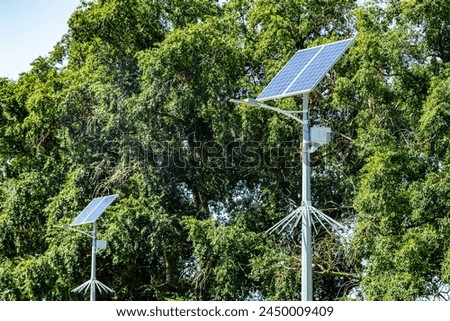 Lamp post with solar panel system on road with blue sky and trees. Autonomous street lighting using solar panels. Street lamp, on batteries from the sun. Alternative renewable energy systems.